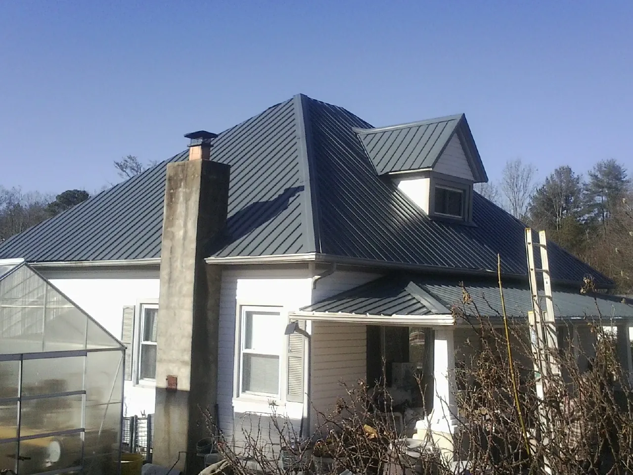 Dark blue standing seam metal roof on a white farmhouse with dormer — Slate & Tile Roof Repair by Roofing Brothers in Eagle Point
