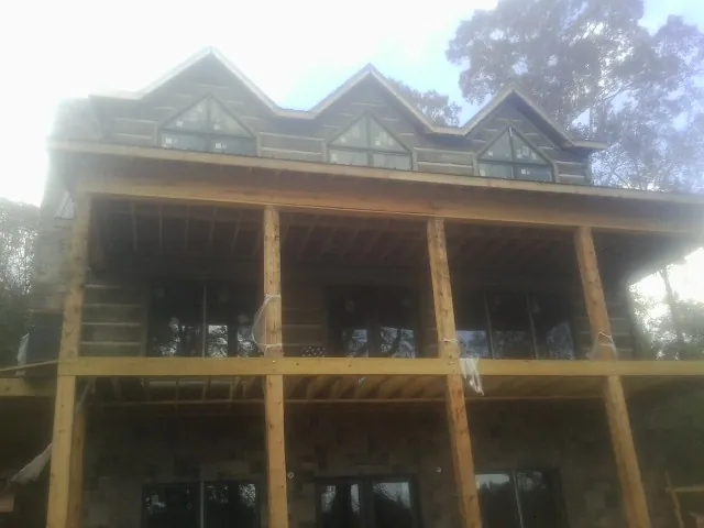 Dormers and porch framing on a large log home under construction — Roof Coating work by our crew in Eagle Point
