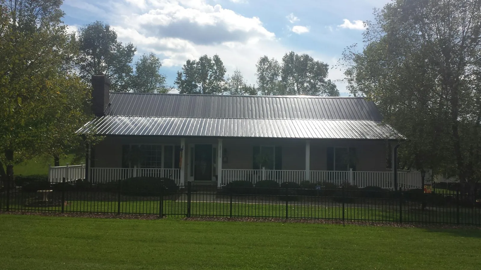 Gray metal roof on a brick ranch with a full width front porch — Gutter Guard Installation work by our crew in Eagle Point