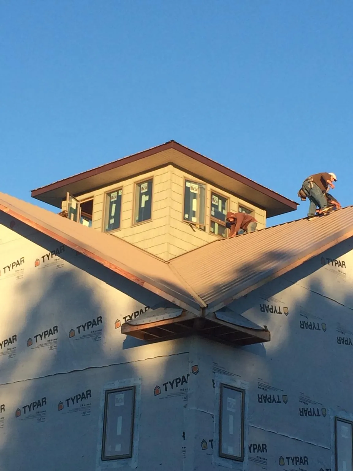 Roofers working around a rooftop cupola on a new metal roof at sunset — Roof Waterproofing in Eagle Point by Roofing Brothers